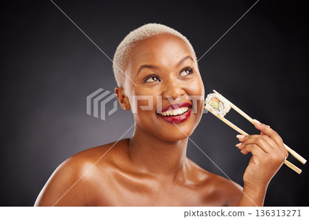 Thinking, face and woman with sushi and chopsticks in studio for healthy eating, beauty or food. Happy black female model with makeup idea on dark background for wellness, diet or seafood advertising Thinking, face and woman with sushi and chopsticks in studio for healthy eating, beauty or food. Happy black female model with makeup idea on dark background for wellness, diet or seafood advertising 136313271