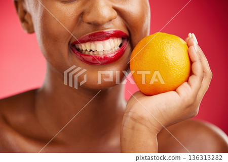Woman, mouth and orange for vitamin C, diet or health and wellness against a red studio background. Closeup of female person smile with lipstick and organic citrus fruit for snack, fiber or food 136313282