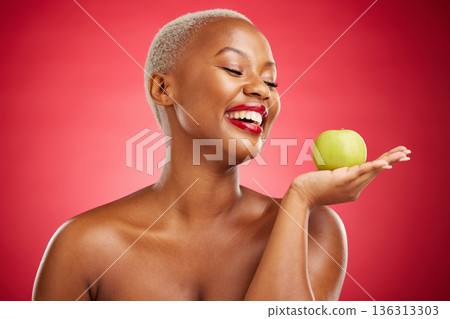 Happy black woman, apple and natural nutrition for diet, health and wellness against a red studio background. African female person smile and palm with organic green fruit for food, snack or meal Happy black woman, apple and natural nutrition for diet, health and wellness against a red studio background. African female person smile and palm with organic green fruit for food, snack or meal 136313303