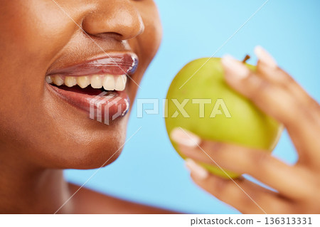 Black woman, mouth and apple in diet, nutrition or health and wellness against a blue studio background. Closeup of African female person eating natural organic fruit for vitamin, fiber or food snack Black woman, mouth and apple in diet, nutrition or health and wellness against a blue studio background. Closeup of African female person eating natural organic fruit for vitamin, fiber or food snack 136313331