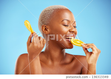 Orange, beauty and nutrition with a model black woman in studio on a blue background biting fruit. Food, skincare and natural with a happy young female person eating a snack for health or wellness Orange, beauty and nutrition with a model black woman in studio on a blue background biting fruit. Food, skincare and natural with a happy young female person eating a snack for health or wellness 136313349