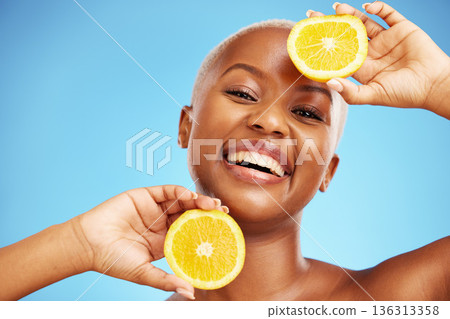 Portrait, orange and beauty with a model black woman in studio on a blue background for nutrition. Smile, fruit and skincare with a happy young person holding a snack for natural health or wellness Portrait, orange and beauty with a model black woman in studio on a blue background for nutrition. Smile, fruit and skincare with a happy young person holding a snack for natural health or wellness 136313358