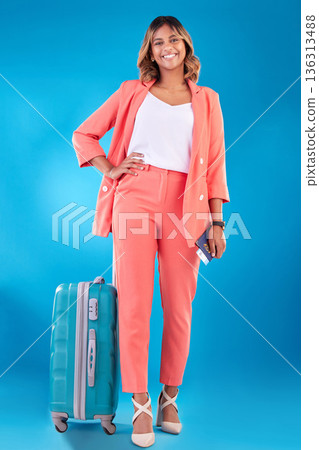 Travel, portrait and a woman with luggage on a blue background for a vacation, journey or flight. Smile, ready and a young Indian girl with a suitcase and passport for a holiday on a backdrop Travel, portrait and a woman with luggage on a blue background for a vacation, journey or flight. Smile, ready and a young Indian girl with a suitcase and passport for a holiday on a backdrop 136313488