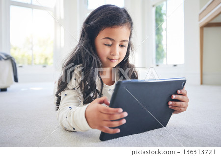 Young girl, tablet and game app or cartoon streaming online with internet, elearning and relax on carpet in house. Watch animation film, female kid at home and website, entertainment and subscription Young girl, tablet and game app or cartoon streaming online with internet, elearning and relax on carpet in house. Watch animation film, female kid at home and website, entertainment and subscription 136313721