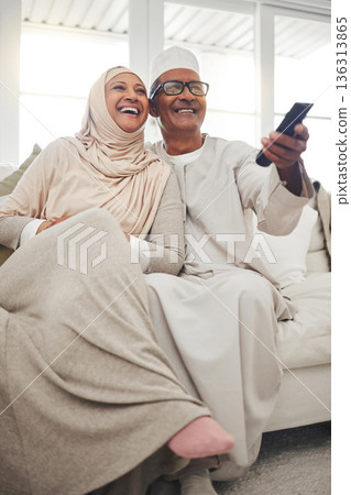 Relax, muslim and watching tv with old couple on sofa for streaming, movie and funny. Television, smile and happy with senior man and woman in living room at home for comedy, retirement and lounge Relax, muslim and watching tv with old couple on sofa for streaming, movie and funny. Television, smile and happy with senior man and woman in living room at home for comedy, retirement and lounge 136313865