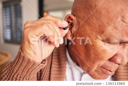 Hearing aid, ear and a senior man with a disability in his home closeup for listening to noise or volume. Healthcare, medical or deaf with a mature male person in his retirement house for wellness 136313968