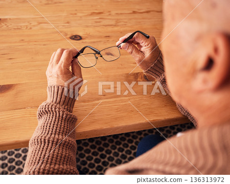 Senior man, hand holding glasses and eye care with vision, prescription lens and designer frame at table. Elderly guy, hands and spectacles for vision, eyesight and health at desk in retirement home Senior man, hand holding glasses and eye care with vision, prescription lens and designer frame at table. Elderly guy, hands and spectacles for vision, eyesight and health at desk in retirement home 136313972