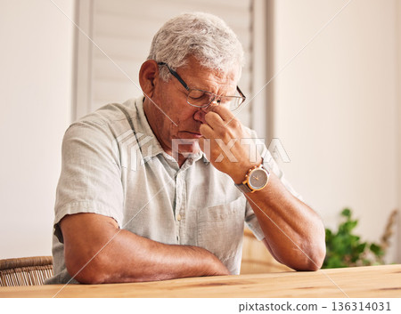 Stress, headache and old man at table in home with glasses, worry and fatigue in retirement. Debt, anxiety and tired, frustrated senior person with mental health problem or crisis, exhausted and sad. 136314031