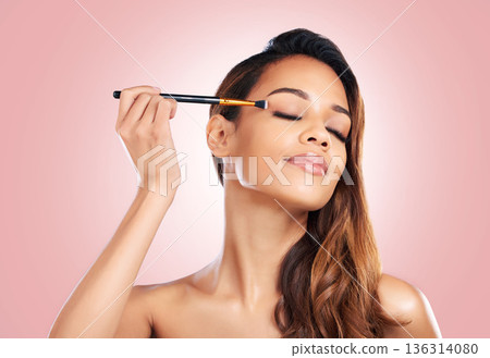 Makeup, eyeshadow and face of woman with brush on pink background for beauty, wellness and luxury. Cosmetology, aesthetic and female person with tools for foundation, cosmetics and glamour in studio Makeup, eyeshadow and face of woman with brush on pink background for beauty, wellness and luxury. Cosmetology, aesthetic and female person with tools for foundation, cosmetics and glamour in studio 136314080