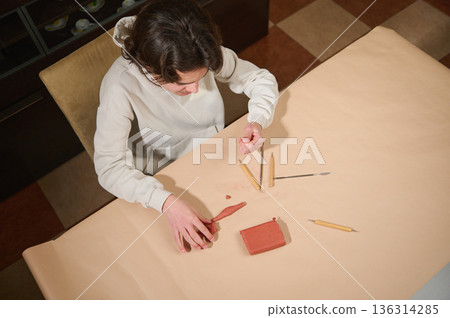 Person Sculpting With Clay At Table Using Various Tools And Red Clay Block Person Sculpting With Clay At Table Using Various Tools And Red Clay Block 136314285
