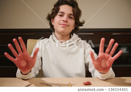 Young Boy At Home Demonstrates Clay Molding With Hands Raised In Creative Hobby Young Boy At Home Demonstrates Clay Molding With Hands Raised In Creative Hobby 136314301