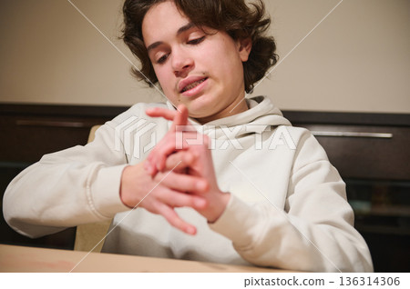 Teen Boy Focused On Clay Hobby At Home, Hands Interlaced In Thoughtful Moment Teen Boy Focused On Clay Hobby At Home, Hands Interlaced In Thoughtful Moment 136314306
