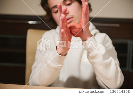 Teen Boy Molding Red Clay At Home, Focused On Hands And Craft Teen Boy Molding Red Clay At Home, Focused On Hands And Craft 136314308