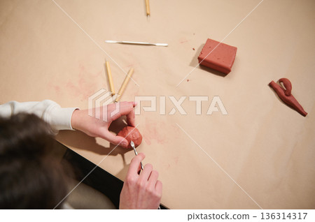 Young Multi-Ethnic Boy Molding Red Clay Ball with Sculpting Tools at Home Hobby Studio Creative Young Multi-Ethnic Boy Molding Red Clay Ball with Sculpting Tools at Home Hobby Studio Creative 136314317