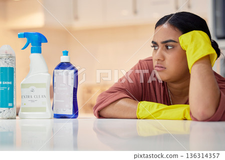 Cleaning, spray bottle and frown with an annoyed woman housekeeper looking at hygiene products in the kitchen. Depression, housekeeping and supplies with a frustrated female cleaner in a home 136314357