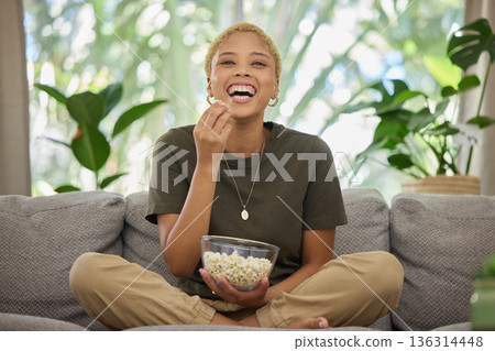 Woman is laughing, popcorn and watch a movie, comedy and entertainment, streaming service and relax at home. Female person, subscription and watching funny film or series with cinema snack on sofa Woman is laughing, popcorn and watch a movie, comedy and entertainment, streaming service and relax at home. Female person, subscription and watching funny film or series with cinema snack on sofa 136314448