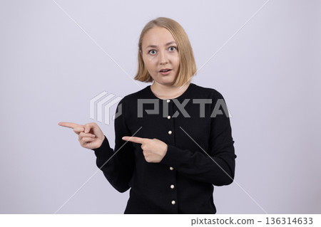 Woman in black shirt pointing sideways with two fingers 136314633