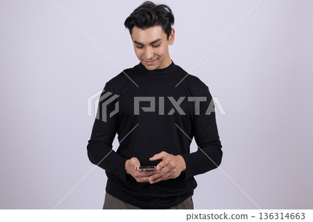 Young man in black turtleneck using a smartphone 136314663