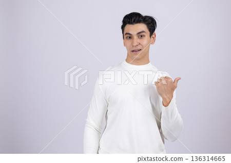 Man in white shirt pointing thumb sideways to copy space Man in white shirt pointing thumb sideways to copy space 136314665