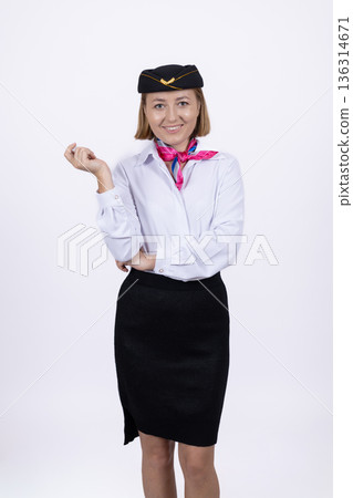 Flight attendant in white blouse and black skirt posing 136314671