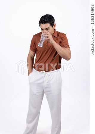Young man in orange polo shirt posing with hand on head 136314698
