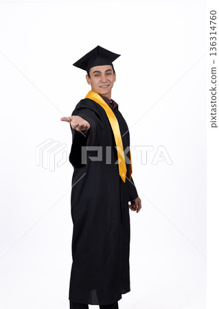 Young male graduate in black gown pointing to side 136314760