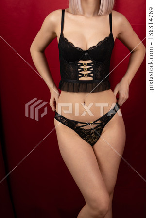 Woman in black bodysuit posing near red curtain Woman in black bodysuit posing near red curtain 136314769