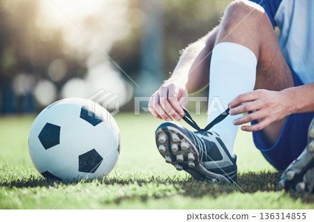 Ball, man and soccer player tie shoes for training, fitness games and performance on field. Closeup, football athlete and lace sneakers on feet, grass pitch and sports competition on stadium ground Ball, man and soccer player tie shoes for training, fitness games and performance on field. Closeup, football athlete and lace sneakers on feet, grass pitch and sports competition on stadium ground 136314855