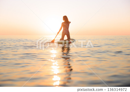 Young woman walking on stand up paddle sup boards by the sea during summer vacation 136314972