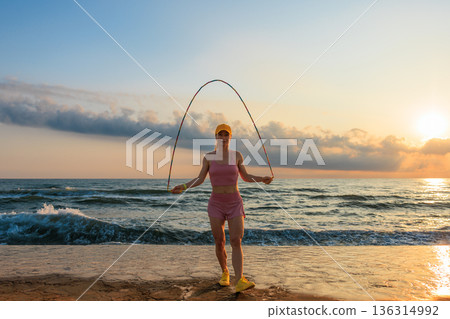Fit woman jumping rope at the beach during summer vacation 136314992