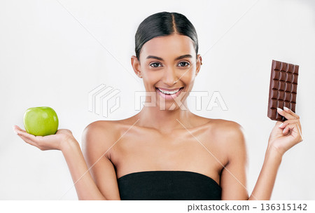 Apple, chocolate and portrait of woman for healthy food choice, sugar and beauty isolated on studio white background. Dessert, green fruit and face of indian person detox, vegan or skincare decision Apple, chocolate and portrait of woman for healthy food choice, sugar and beauty isolated on studio white background. Dessert, green fruit and face of indian person detox, vegan or skincare decision 136315142