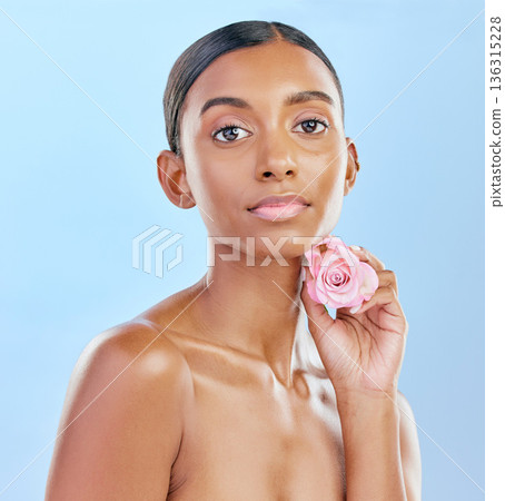 Woman, rose and natural beauty with cosmetics and eco friendly skincare on blue background. Flower, nature and sustainable dermatology with skin glow, female model and portrait in studio Woman, rose and natural beauty with cosmetics and eco friendly skincare on blue background. Flower, nature and sustainable dermatology with skin glow, female model and portrait in studio 136315228