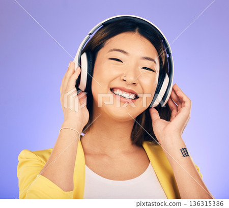 Headphones, music and happy Asian woman in studio listening to audio, streaming song and radio. Entertainment, subscription and female person relax with earphones for album on purple background 136315386