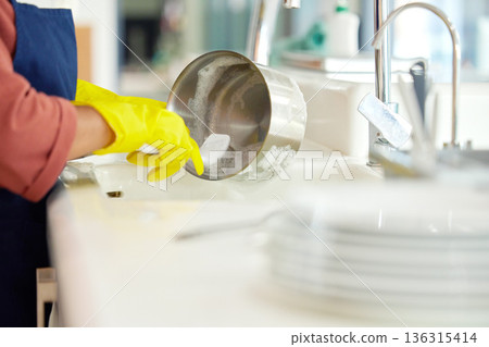 Hands of woman, gloves and washing dishes in kitchen, brush chores and house work, cleaner service and home care. Cleaning, soap and water, housekeeper working in apartment with dirt and foam at sink Hands of woman, gloves and washing dishes in kitchen, brush chores and house work, cleaner service and home care. Cleaning, soap and water, housekeeper working in apartment with dirt and foam at sink 136315414