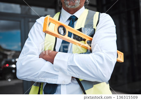 Man, arms crossed and architect has level, construction and confident in city, maintenance and project management. Urban infrastructure, architecture and male contractor with tools and professional 136315509