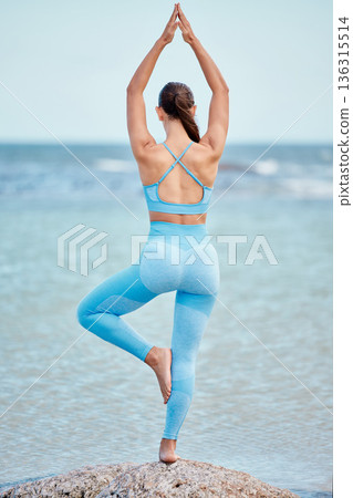 Yoga, fitness and back view of woman at the beach for workout or training as health, mindfulness and wellness routine. Healthy, body and person training a chakra by doing tree pose at the sea Yoga, fitness and back view of woman at the beach for workout or training as health, mindfulness and wellness routine. Healthy, body and person training a chakra by doing tree pose at the sea 136315514