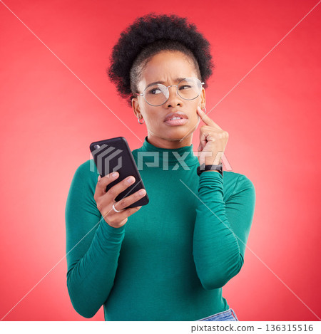 Thinking, phone and black woman in studio confused by text, application or how to steps on red background. Doubt, why and African person with questions for scam or spam contact on smartphone 136315516