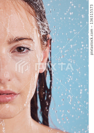 Closeup, portrait and woman with water, shower or hygiene on a blue studio background. Face, female person or model with drops, liquid or aqua for washing, cleaning or morning routine with wellness 136315573