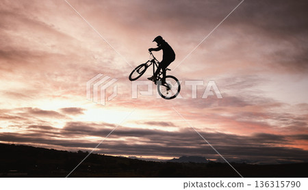 Sunset, dirt bike and jump with action in outdoor with sport in nature for adventure or risk. Motorcycle, silhouette and freedom with training or sky with speed in desert with person driving. Sunset, dirt bike and jump with action in outdoor with sport in nature for adventure or risk. Motorcycle, silhouette and freedom with training or sky with speed in desert with person driving. 136315790