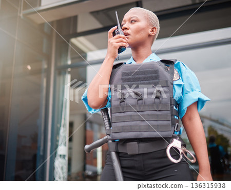 Police, walkie talkie and patrol with a black woman officer outdoor on a city street for law enforcement. Radio, communication and a female security guard talking during crime prevention for safety Police, walkie talkie and patrol with a black woman officer outdoor on a city street for law enforcement. Radio, communication and a female security guard talking during crime prevention for safety 136315938