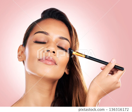 Makeup, eyeshadow and face of woman with brush on pink background for beauty, wellness and luxury. Cosmetology, aesthetic and female person with tools for foundation, cosmetics and glamour in studio 136316172