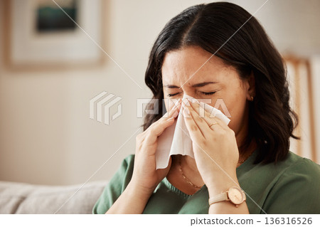 Tissue, blowing nose and woman in a living room with flu, cold and hay fever, crisis or viral infection in her home. Sneezing, allergies and person with health risk in a lounge or coughing illness 136316526