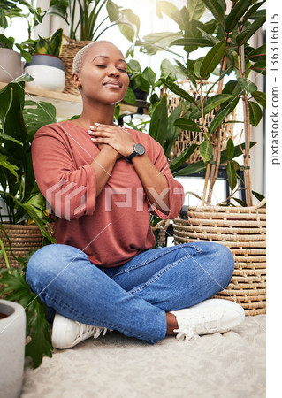 Calm, peace and young woman by plants for breathing exercise in meditation in a greenery nursery. Breathe, gratitude and African female person with a relaxing zen mindset by indoor greenhouse garden. 136316615