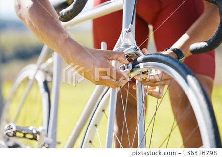 Bicycle, wheel and a man outdoor fixing puncture or problem while cycling. Bike, hands and a sports person, cyclist or athlete check air for maintenance, safety or repair on broken or flat tyre 136316798