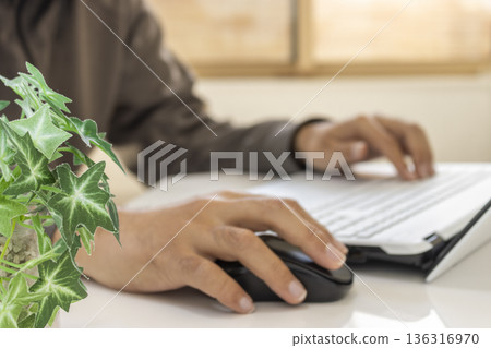 一張照片顯示,一名男子在明亮的房間裡靠窗遠端辦公(焦點在前景的植物上,沒有拍到人臉)。 一張照片顯示,一名男子在明亮的房間裡靠窗遠端辦公(焦點在前景的植物上,沒有拍到人臉)。 136316970