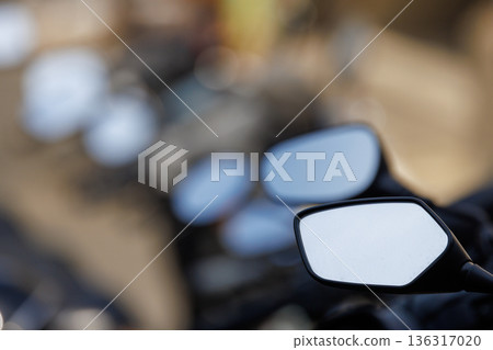 Rearview mirror and blur of motorcycles parked side by side (close-up) Rearview mirror and blur of motorcycles parked side by side (close-up) 136317020