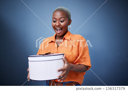 Black woman, present package and surprise in studio with excited smile, birthday and blue background. African girl, happy and wow with box, gift and fashion for celebration, winner and birthday party Black woman, present package and surprise in studio with excited smile, birthday and blue background. African girl, happy and wow with box, gift and fashion for celebration, winner and birthday party 136317379