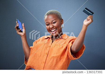 Winner, phone and credit card with a black woman online shopping in studio on a gray background. Mobile, ecommerce and wow with a happy young female shopper in celebration of deal or sale success Winner, phone and credit card with a black woman online shopping in studio on a gray background. Mobile, ecommerce and wow with a happy young female shopper in celebration of deal or sale success 136317391