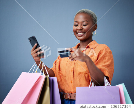 Bags, retail and black woman with a credit card, smartphone or ecommerce on a grey studio background. Female person, shopper or model with cellphone, boutique items or purchase with shopping or smile Bags, retail and black woman with a credit card, smartphone or ecommerce on a grey studio background. Female person, shopper or model with cellphone, boutique items or purchase with shopping or smile 136317394