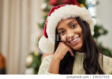 Happy woman, portrait and Christmas hat for celebration, festive season or gift giving time at home. Face of female person with smile in relax for holiday, weekend or December party by tree in house Happy woman, portrait and Christmas hat for celebration, festive season or gift giving time at home. Face of female person with smile in relax for holiday, weekend or December party by tree in house 136317458